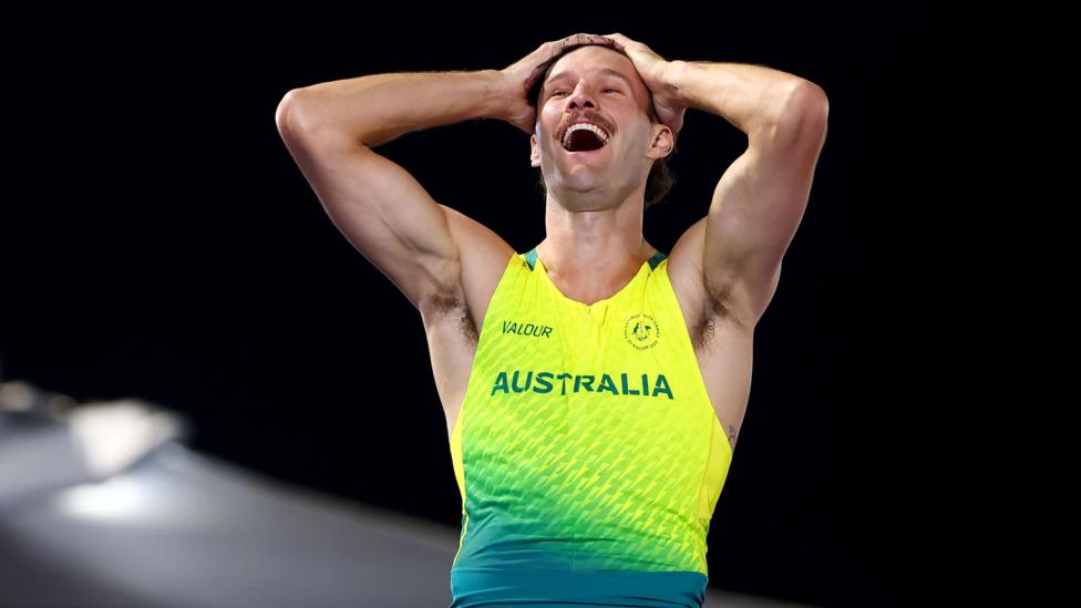 Kurtis Marschall of Team Australia in yellow Australian kit, is smiling broadly, his hands on his head. He looks very happy and has a nice moustache.