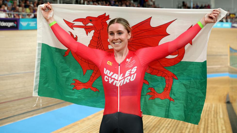 Emma Finucane of Team Wales celebrates her victory in the Women's Sprint Finals by holding up a Welsh flag.