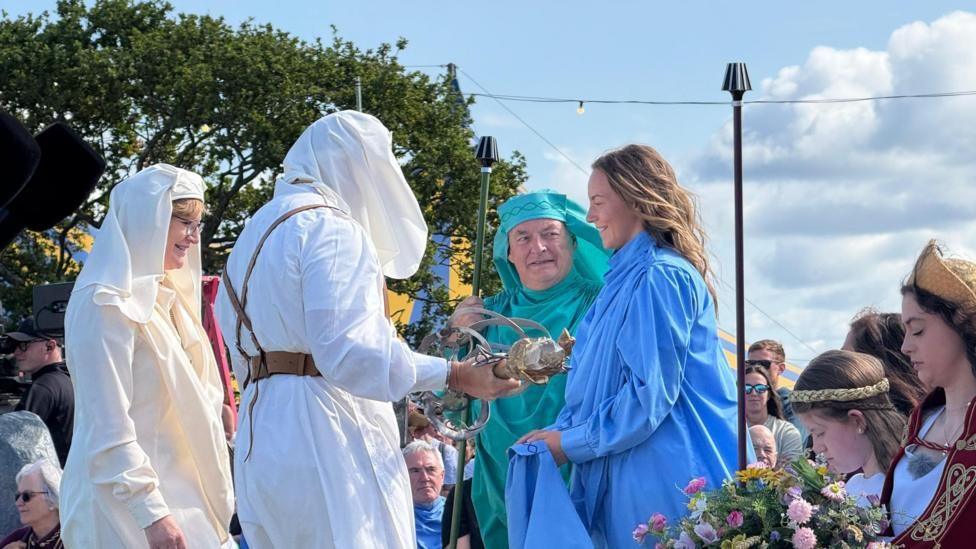 People in white, blue and green robes speak