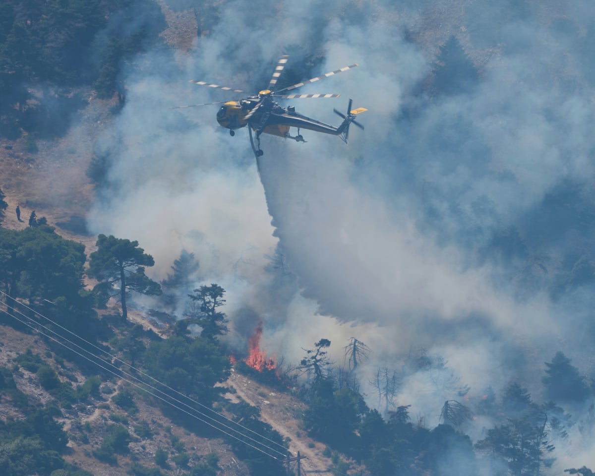 A firefighting helicopter drops water over a wildfire on Mount Kithairon near Porto Germeno, northwest of Athens, Greece.