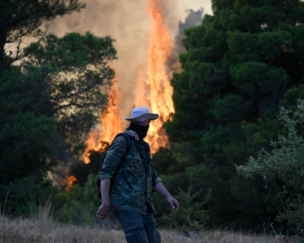 A man watches flames rising during a wildfire near Porto Germeno, northwest of Athens, Greece.