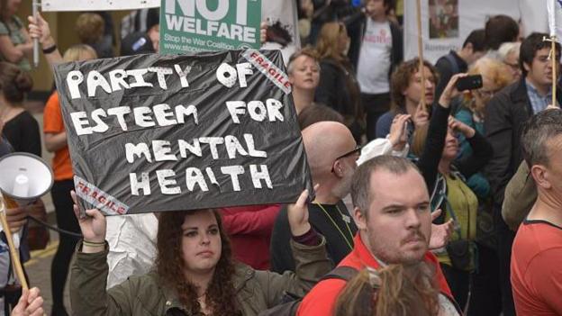 People demonstrating in the street in Manchester, England. One campaigner is holding up a placard that says