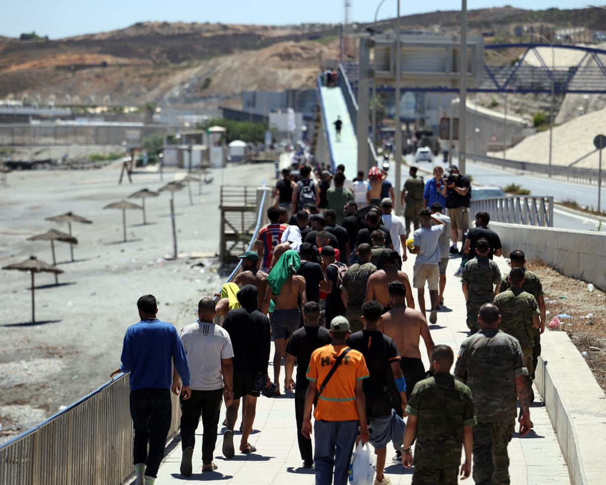 A group of migrants approach the border post to make their way back to Morocco, escorted by Spanish infantry soldiers, in the Spain’s north African enclave of Ceuta.