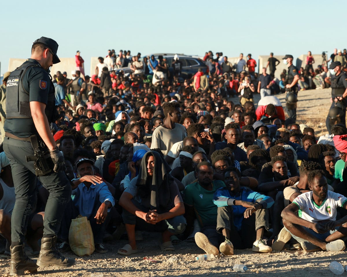 Migrants wait in line to receive food and beverage from the Red Cross, following mass crossings of migrants on foot and by sea from Morocco into Spanish territory, in Ceuta, Spain.