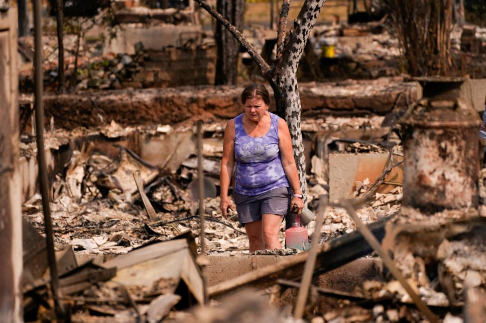 A woman in Spokane, Washington, surveys the damage of her burned down home