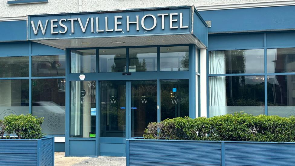 A hotel painted royal blue with several large widows and a sign saying Westville Hotel