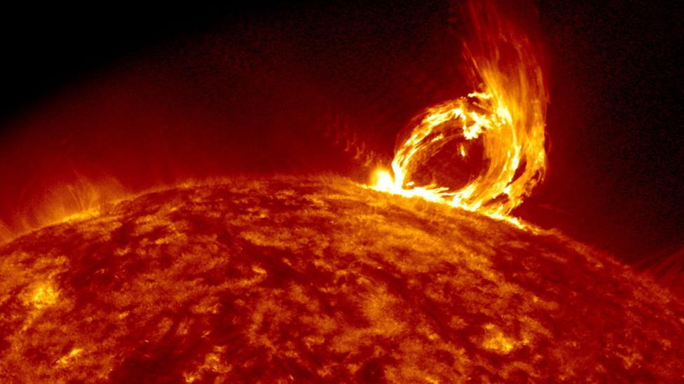 The image shows the fiery orange surface of the Sun with an ejection of what looks like an arch of flames protruding from the surface on the right. This is a coronal mass ejection - a sudden blast of solar plasma and magnetic fields that the Sun sends into space