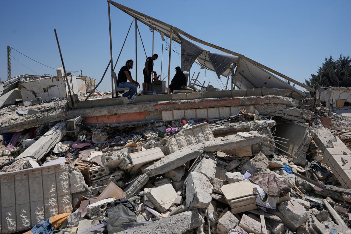 Three people sat atop the rubble of their home.