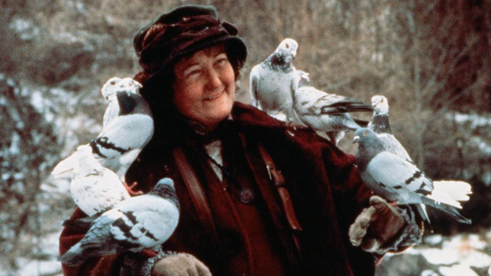 Brenda Fricker with several birds perched on her arms in a scene from Home Alone 2