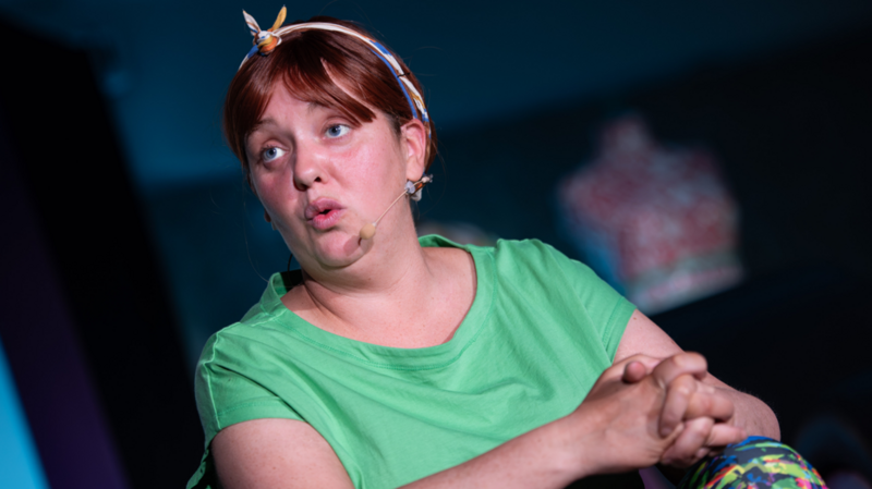 Caroline Curran, the actress in the role of Ciara. She is a woman with fair to brown hair, with a hair band. She is wearing a green t-shirt. 