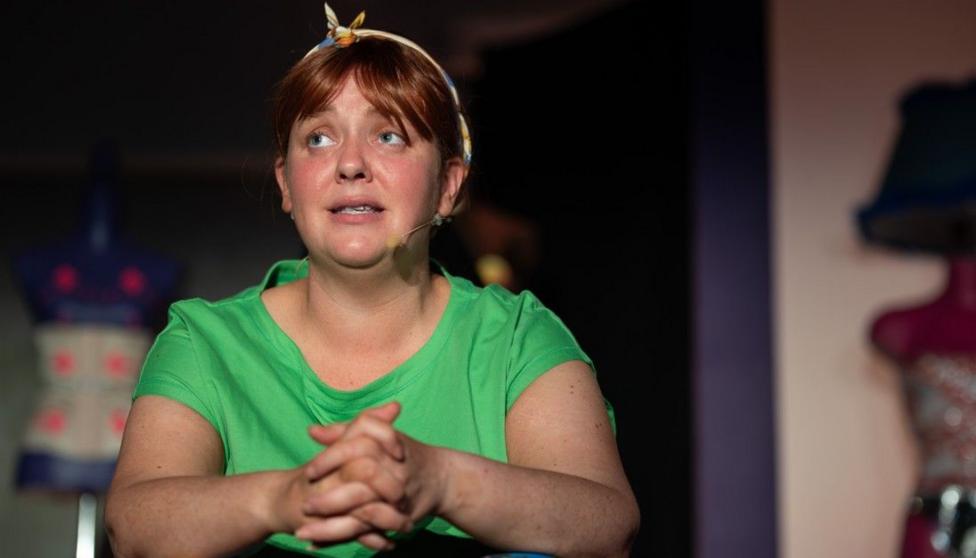 Caroline Curran, a woman with fair to brown hair, wearing a hair band and green t-shirt. 