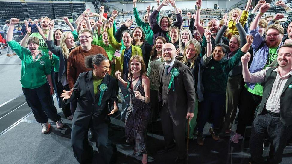A large group of Green MSPs and supporters celebrating their wins in the Glasgow election count hall.