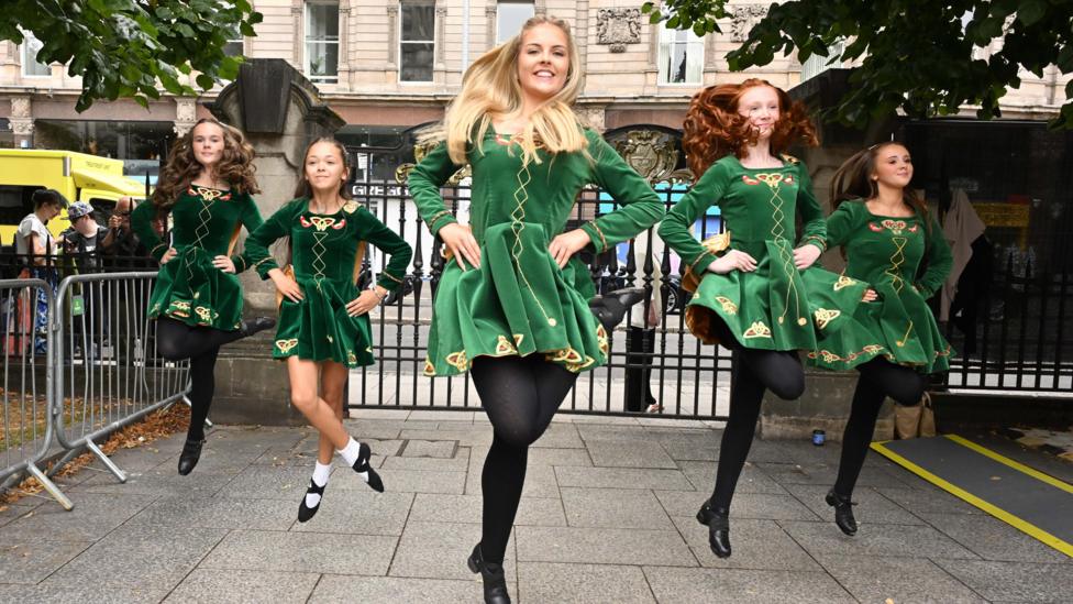 Five Irish dancers in green dresses and black tights.