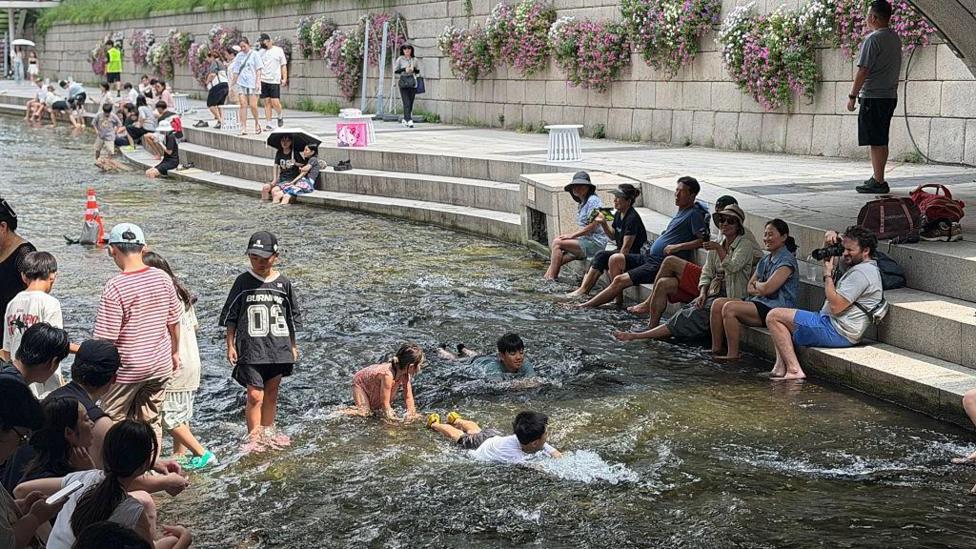 Local residents and tourists cool off at Cheonggyecheon stream