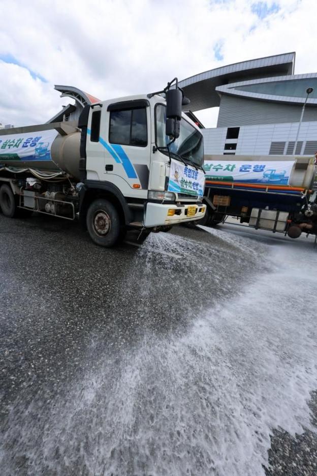 A sprinkler truck sprays water on the road