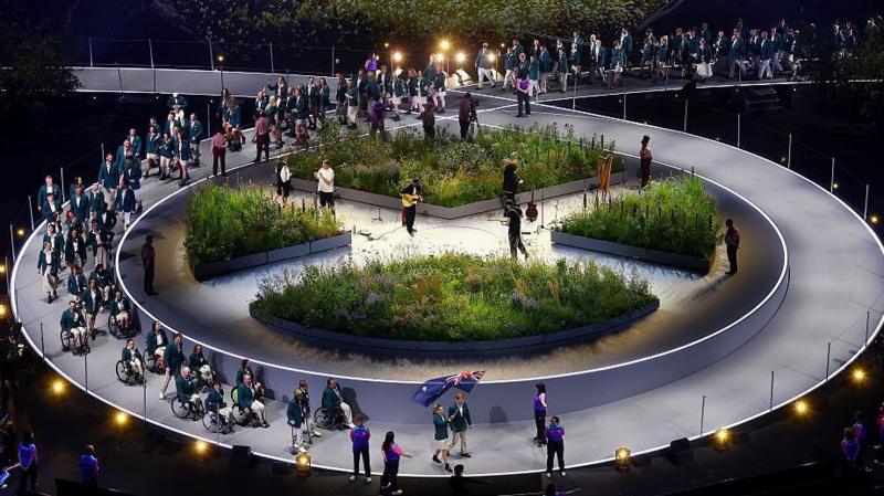 Athletes walking out at the Commonwealth Games opening ceremony, making their way around a circular stage set, with a garden in the middle of it.
