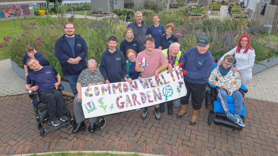 Workers and people who use Parklea;s facilities standing in front of the Saltire garden, on display in a new location