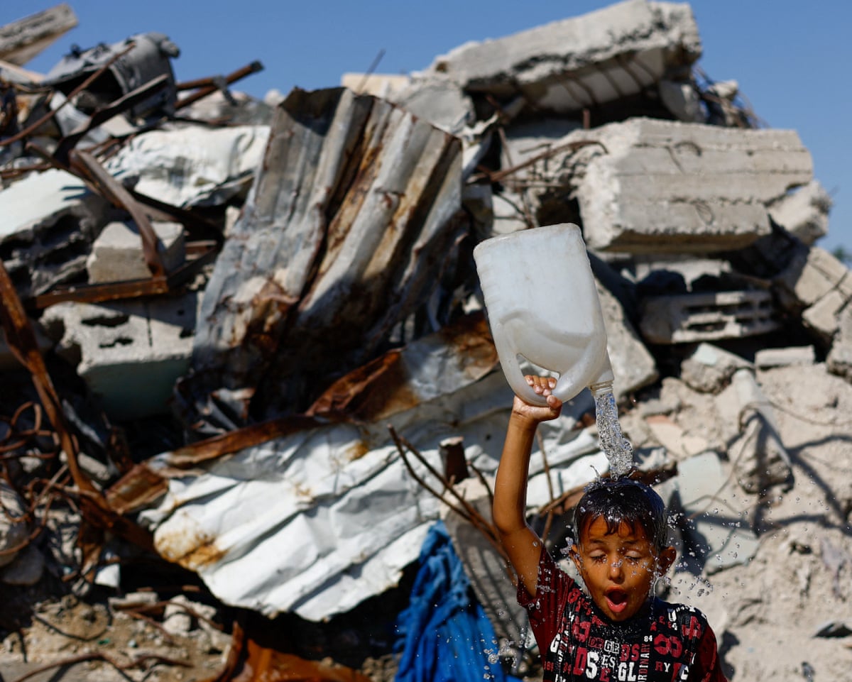 A child pours water over their head from a plastic container
