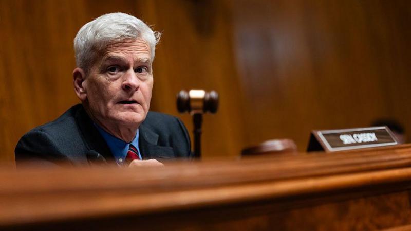 Bill Cassidy, who has grey hair and a blue shirt with a red tie, holds a gavel during a hearing on Capitol Hill.