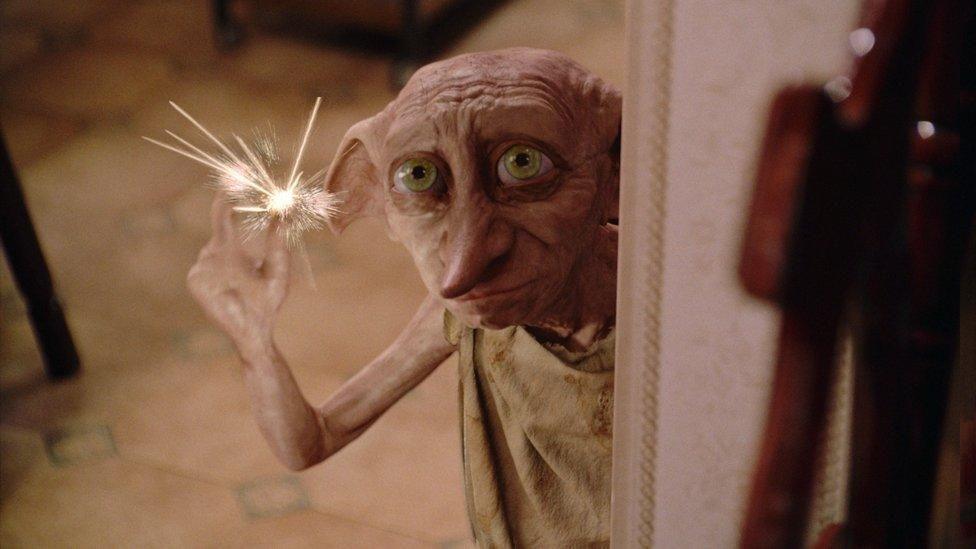 A computer-generated image of Dobby. He is a small creature, with a face similar to a human's but with pink skin, large green eyes, long pointy ears and a long pointy nose. He is wearing a light brown coloured sack for clothes.