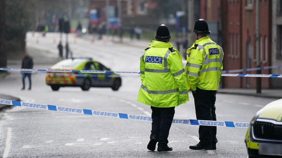 Two officers stand with their backs to the camera next to police tape with a police car in the road in the background in Leicester city centre on Wednesday morning.