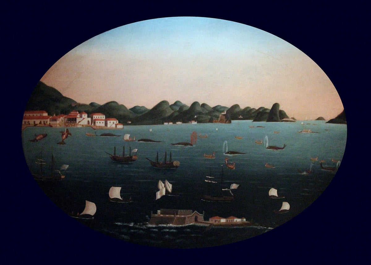 A naive-style of painting in an oval frame showing boats and ships in a bay surrounding whales, one of which is spouting blood