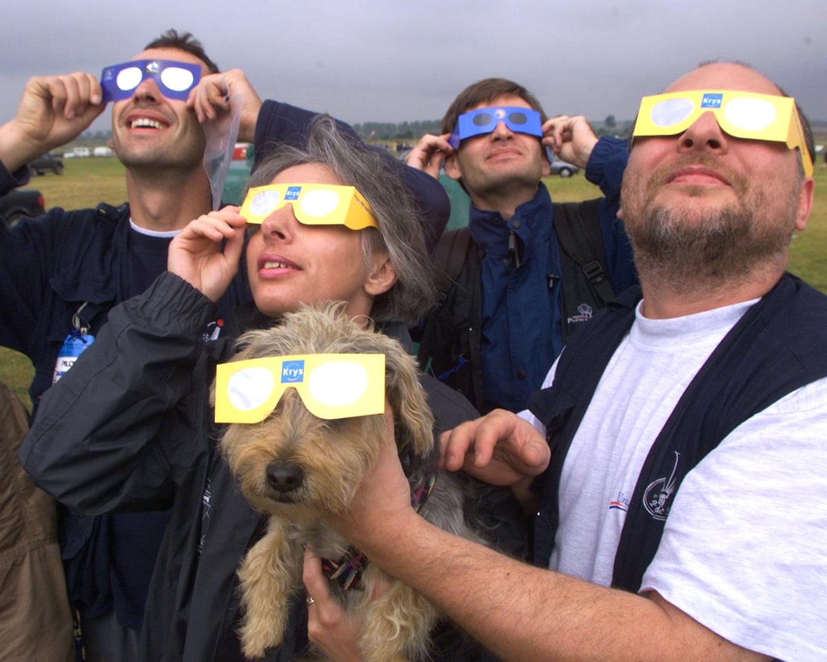 Several people and a well-equipped dog wait eagerly for the clouds to clear in order to watch the solar eclipse in former Nato airbase in Chambley.