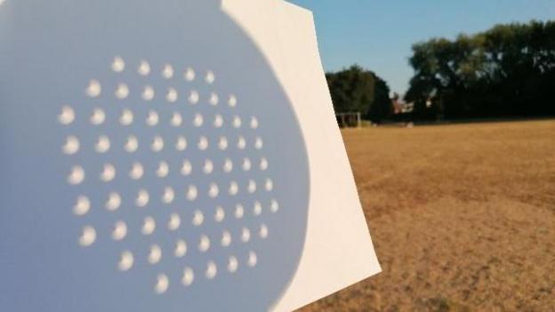 The solar eclipse visible through a colander
