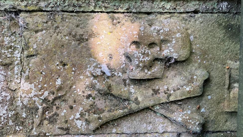 A skull and cross bones carved in a sandstone block in Chapel Yard Cemetery.