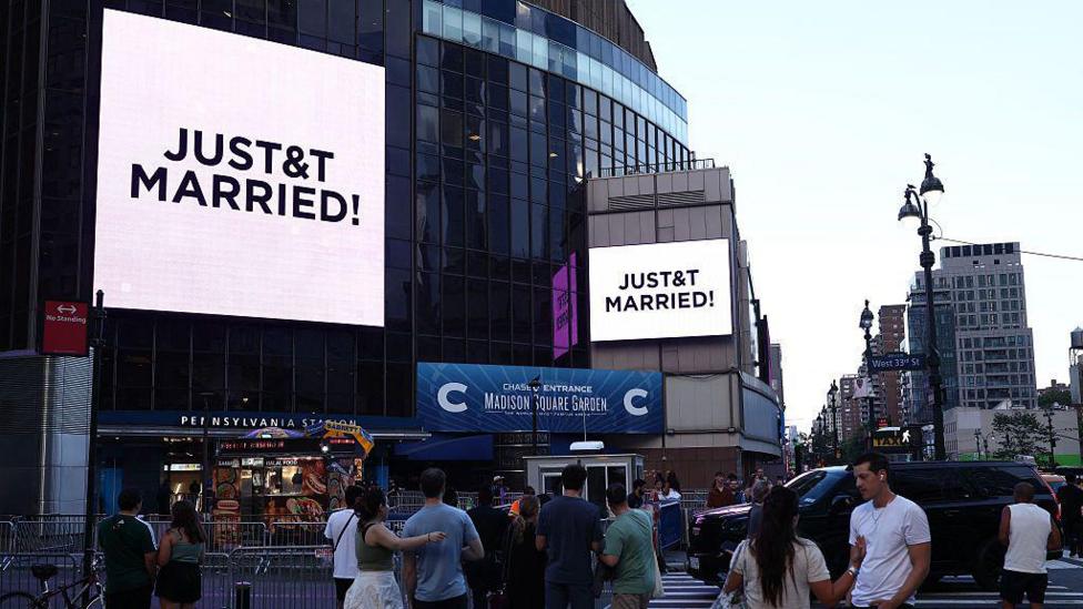 People watch giant screens showing the message