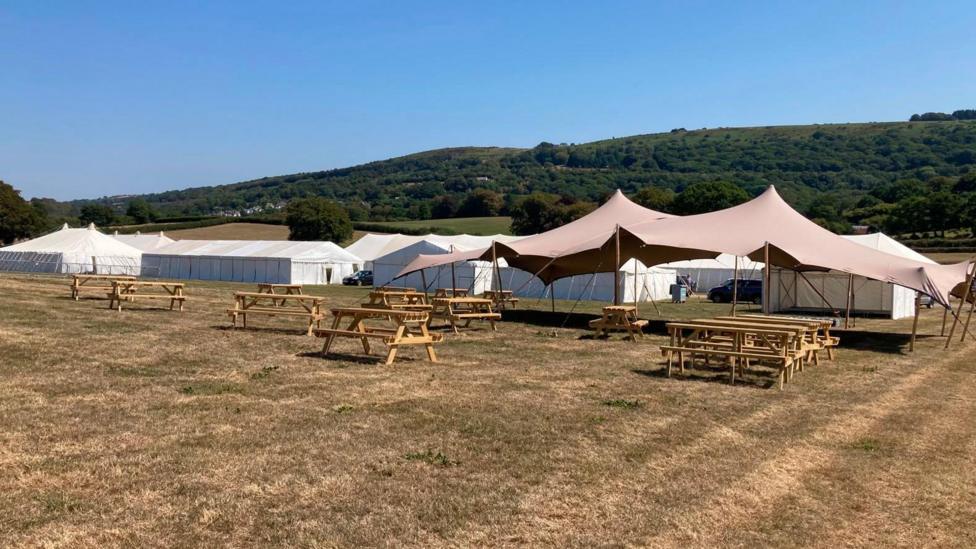 A picture of dry fields with tents and chairs on it.