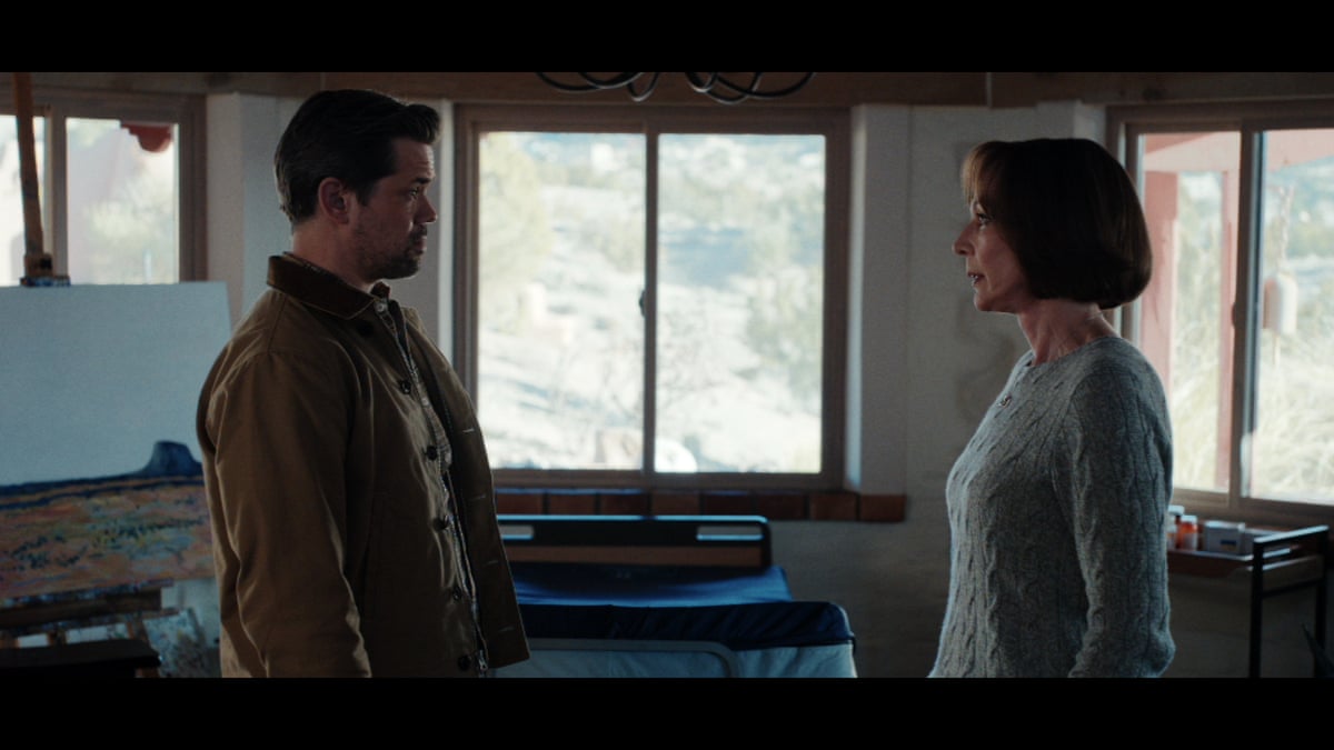 They stand opposite each other in a dark room
