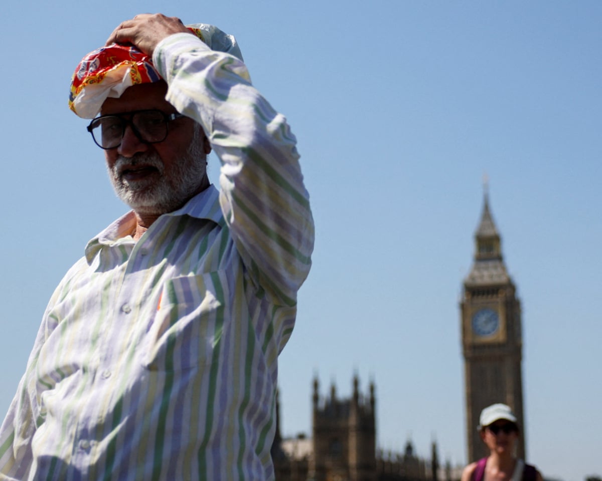 A man walks, with the Elizabeth Tower, more commonly known as Big Ben, visible in the background, during a heatwave in London, Britain.