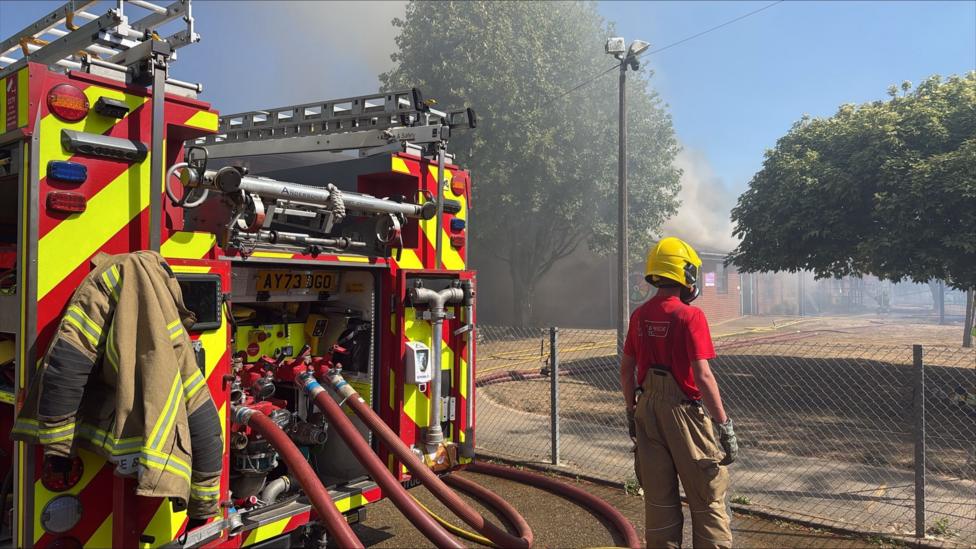Fire officer stands next to a fire engine outside Thomas Bullock Primary Academy.
