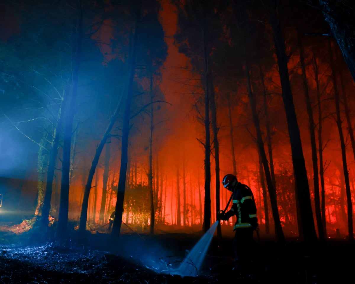 A firefighter hoses down the charred ground as flames continue to burn in the Landes forest in Luglon, southwestern France.