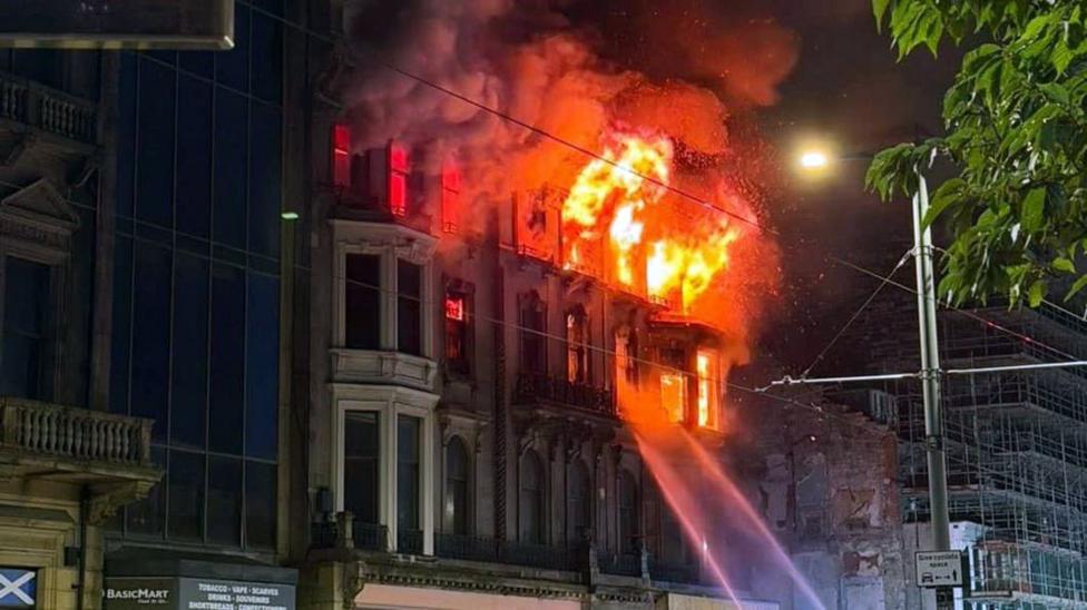 An old Victorian building on fire with jets of water directed at the flames