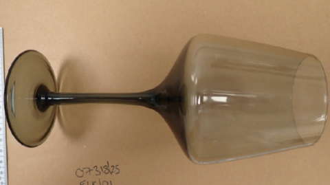 A police evidence image of a wine glass next to two rulers