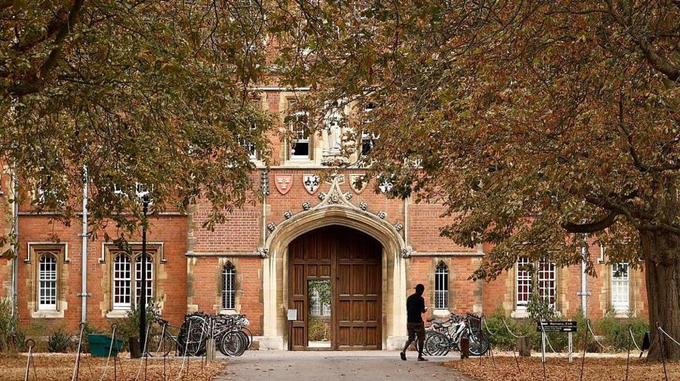 The door of Jesus College at the University of Cambridge surrounded by trees.