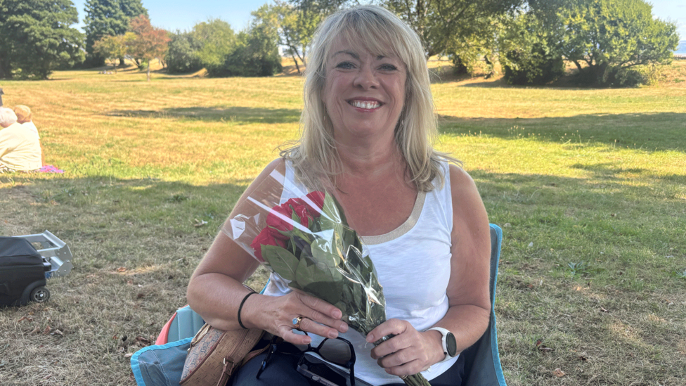 Angela Powell holds flowers ahead of Saturday's tribute