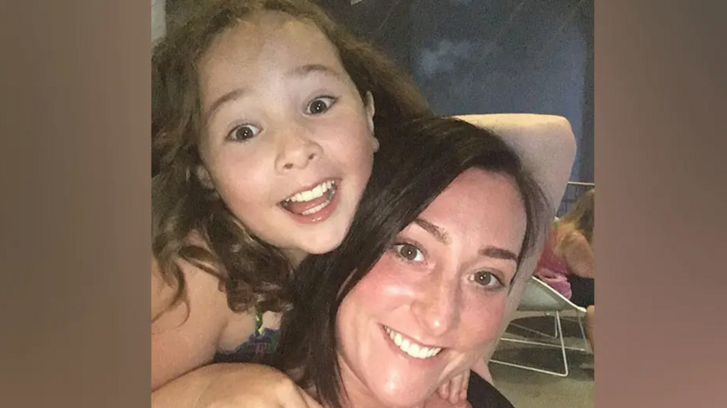 Milly Main smiling while looking at the camera. She has long, brown hair. She is on the back of Kimberly Darroch, who has long, black hair and is also smiling at the camera.