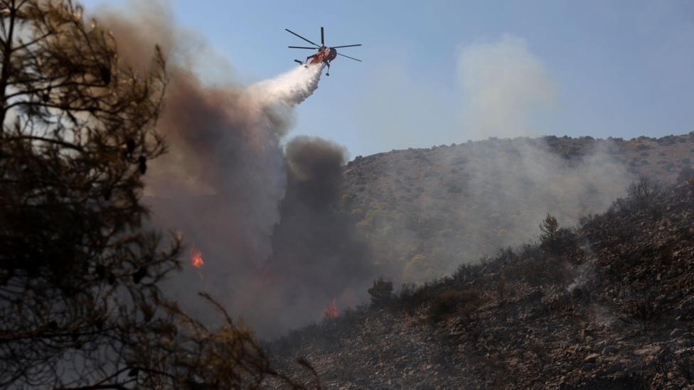 A firefighting helicopter operates to extinguish a wildfire on Salamina Island