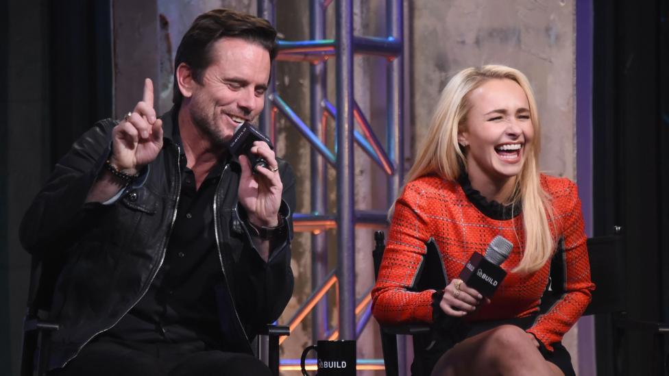 Hayden Panettiere sitting next to Charles Esten, both holding microphones at a Q&A event and laughing heartily