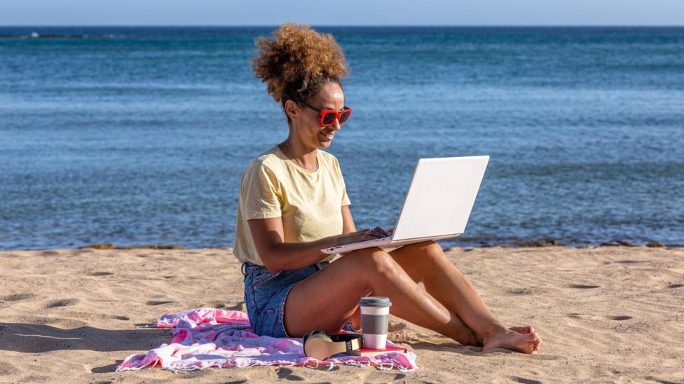 A woman with her laptop on the beach
