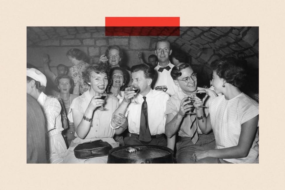 A black and white photo of people in a bar drinking