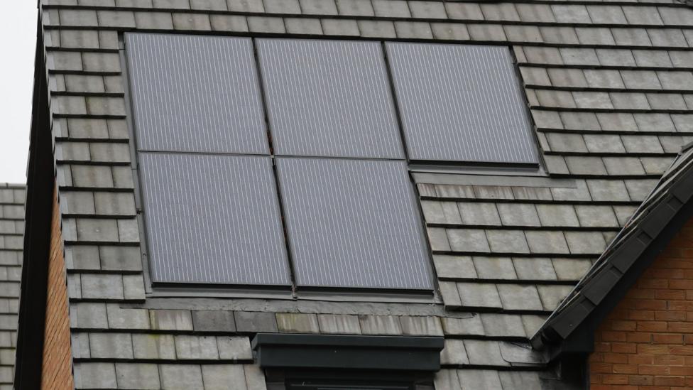 Five solar panels on the roof of a house.