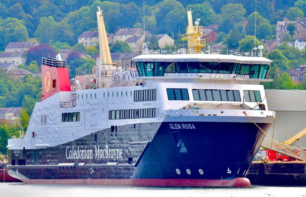 A large black and white ship with red funnels, moored at a quayside
