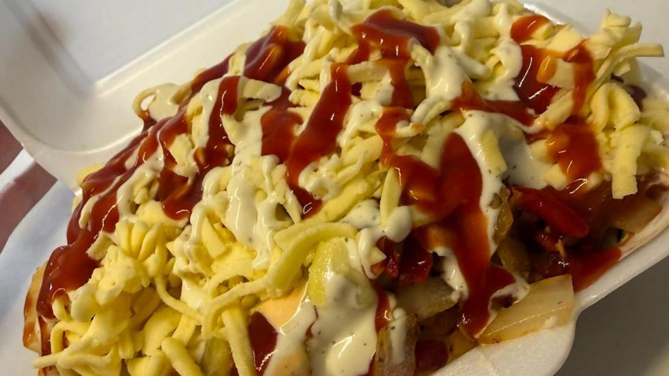 A large chicken box in a plastic container with a number of sauces
