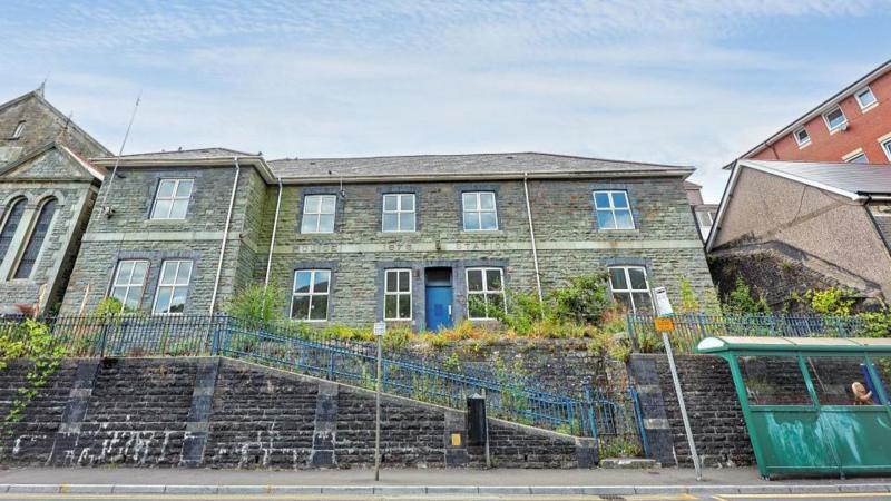 A street view of the police station shows blue railings and sloped walkway access to the police station high above a bus stop