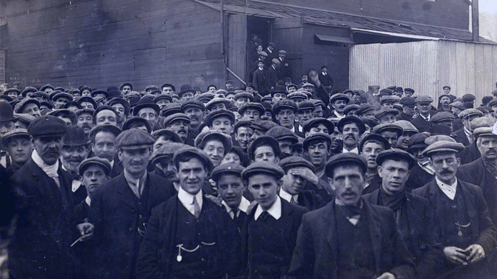 Massive crowd of striking miners, the majority in flat caps, shirt collars and jackets