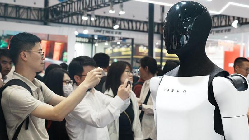 People snap pictures of Tesla's Optimus humanoid prototype at an exhibition in China.